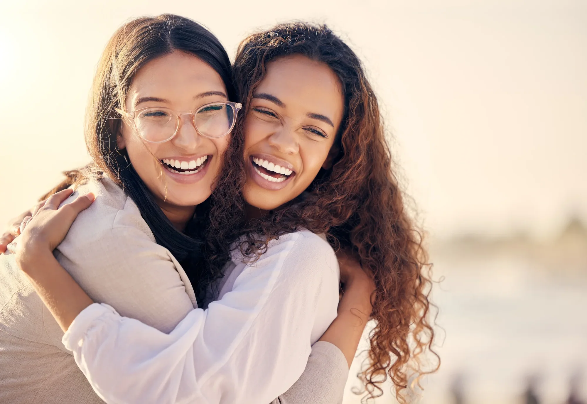 Two friends smiling together in bright natural light.