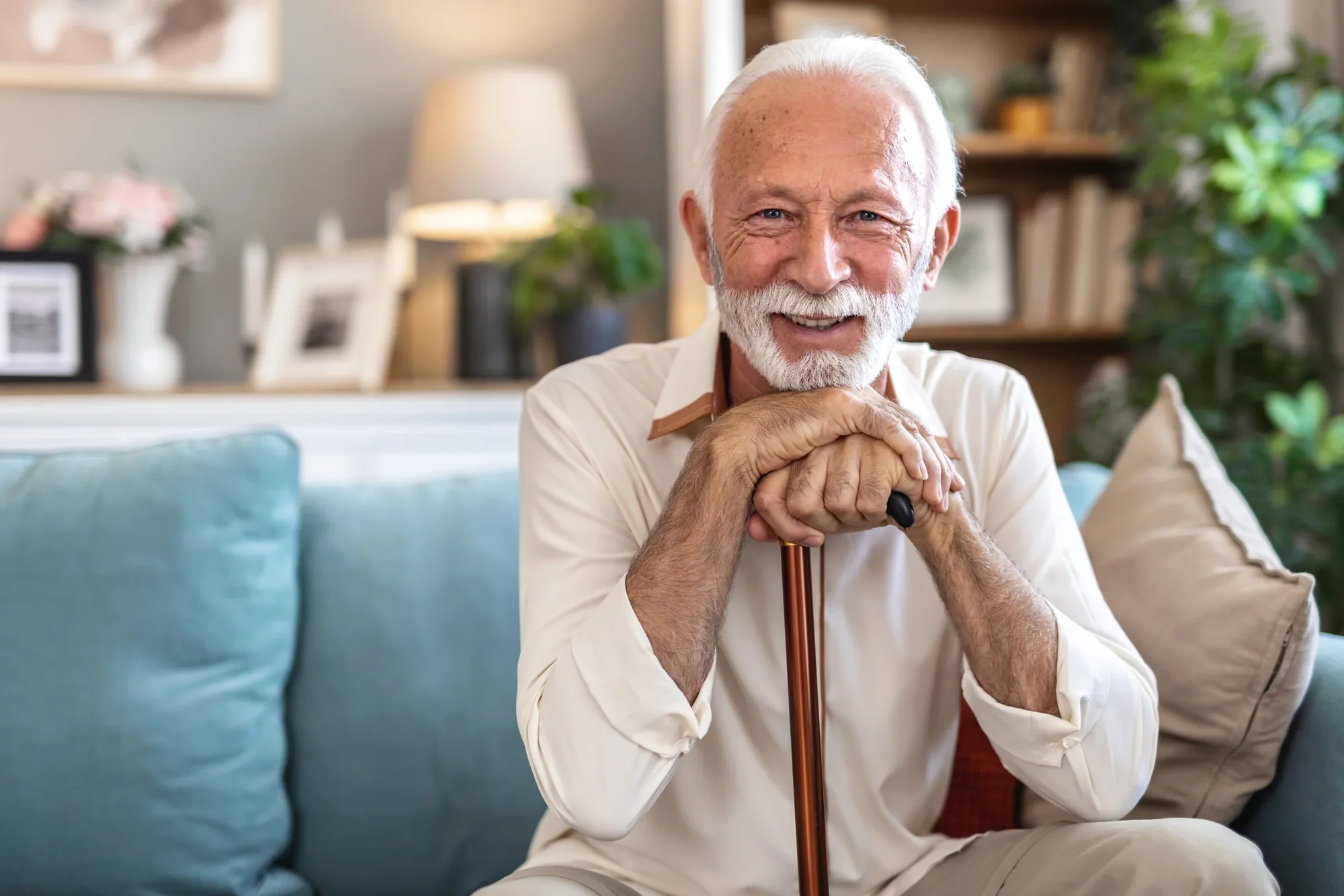 An older smiling man seated comfortably at home.