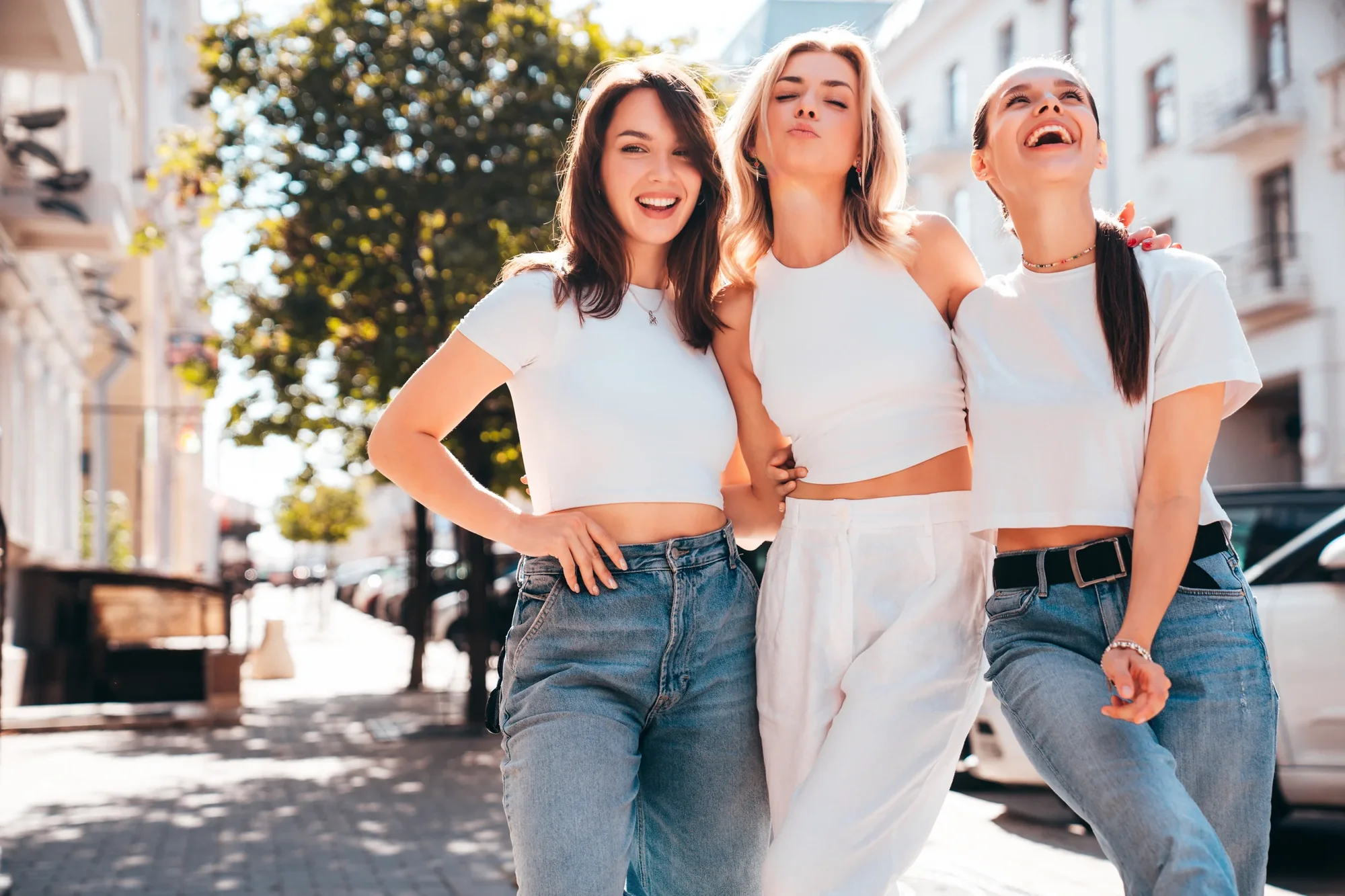 Three smiling friends walking together outdoors.